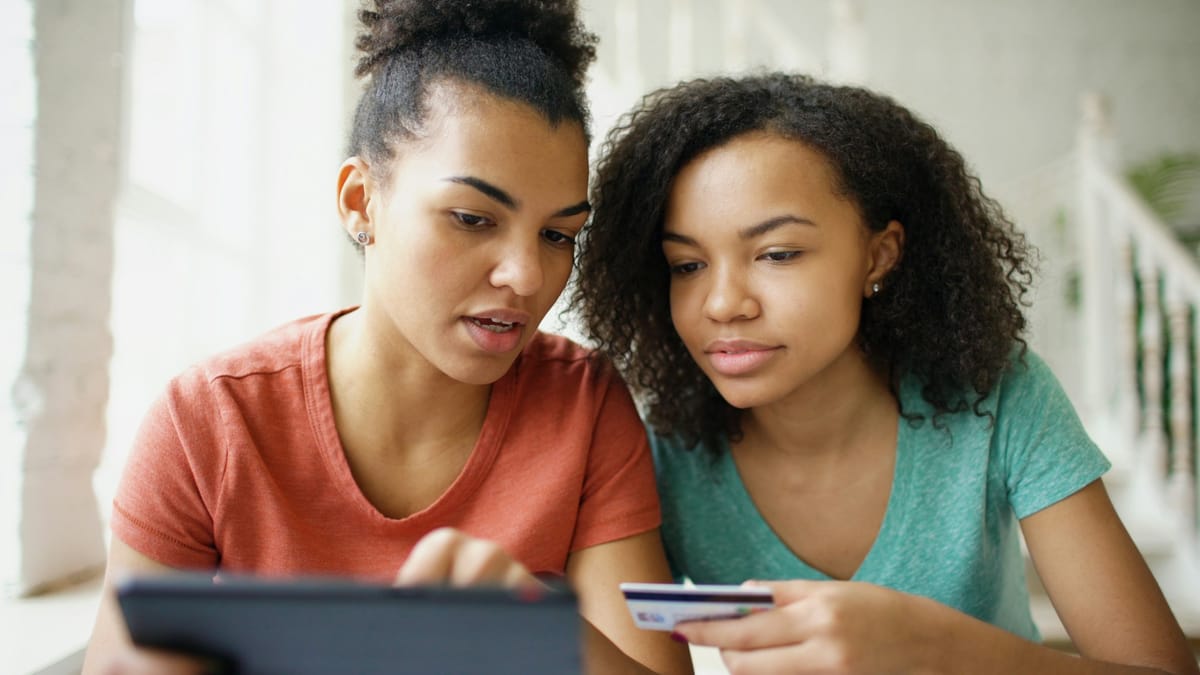 A parent and teenager looking over a simple monthly budget at a kitchen table