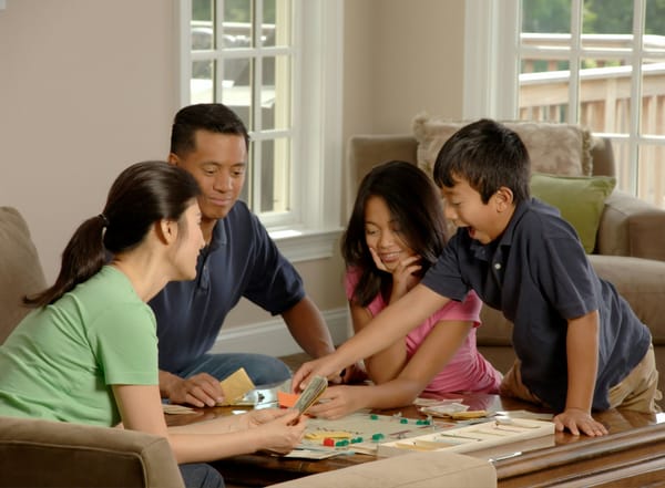 A family seated around a table playing a board game with car