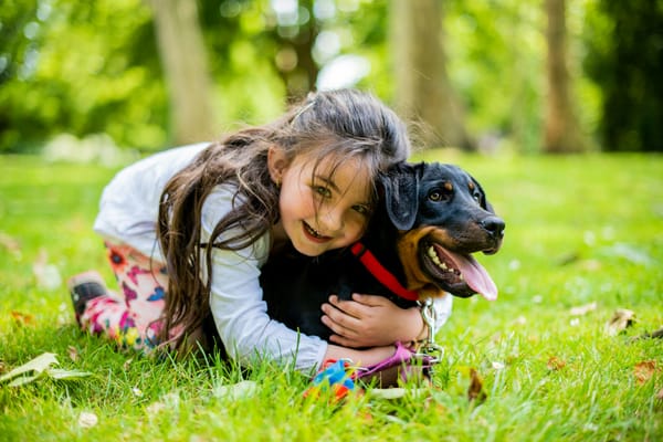 A young child sitting on the floor next to a family pet