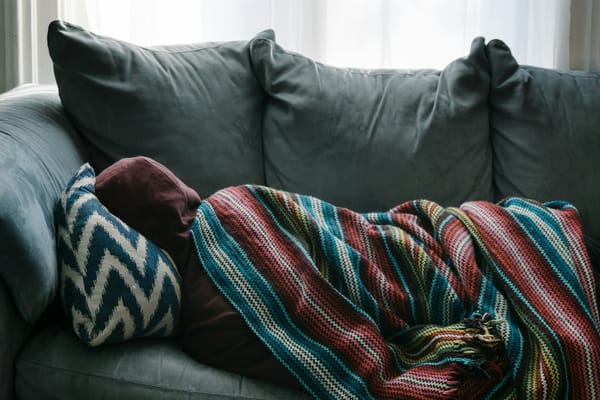 Child resting in bed with a blanket and a cup of water